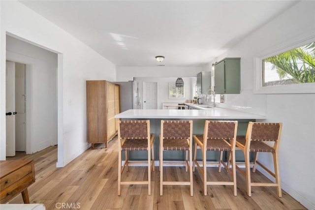 2082 Harris St, San Luis Obispo, CA 93401 - kitchen with green cabinets, a peninsula, light wood-style floors, and a breakfast bar area