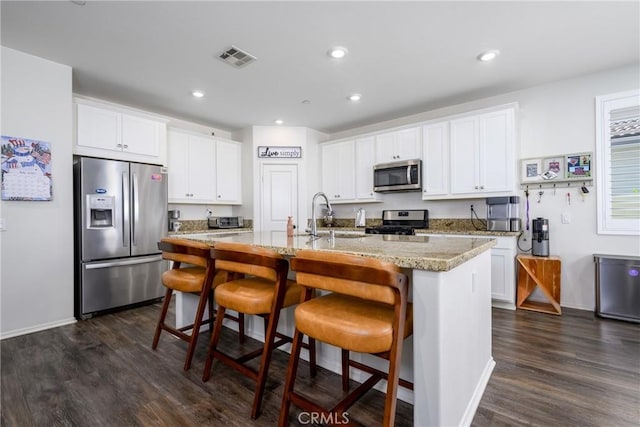 30159 Honor Ct, Menifee, CA 92584 - kitchen featuring stainless steel appliances, dark wood-style floors, white cabinets, a kitchen bar, and recessed lighting