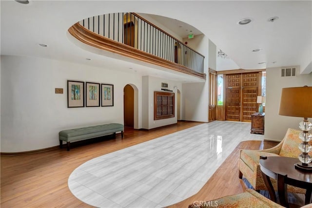6272 Riviera Cir, Long Beach, CA 90815 - living area featuring arched walkways, light wood finished floors, a towering ceiling, and recessed lighting