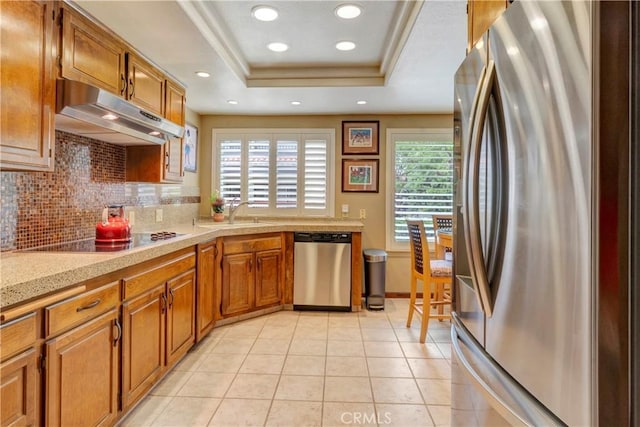 6272 Riviera Cir, Long Beach, CA 90815 - kitchen featuring appliances with stainless steel finishes, under cabinet range hood, tasteful backsplash, brown cabinetry, and recessed lighting