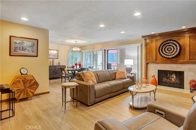6272 Riviera Cir, Long Beach, CA 90815 - living room with a tiled fireplace, light wood-type flooring, recessed lighting, a chandelier, and a textured ceiling