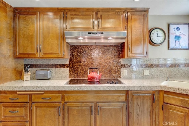 6272 Riviera Cir, Long Beach, CA 90815 - kitchen with under cabinet range hood, electric cooktop, decorative backsplash, light stone countertops, and brown cabinets