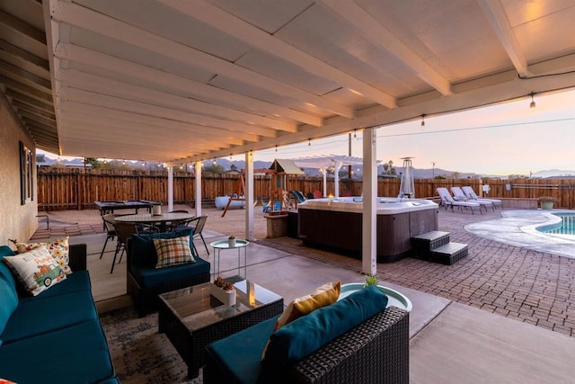 6636 Indian Cove Rd Unit 29, Palms, CA 92277 - patio terrace at dusk featuring an outdoor living space, a hot tub, a patio area, a fenced backyard, and outdoor dining space