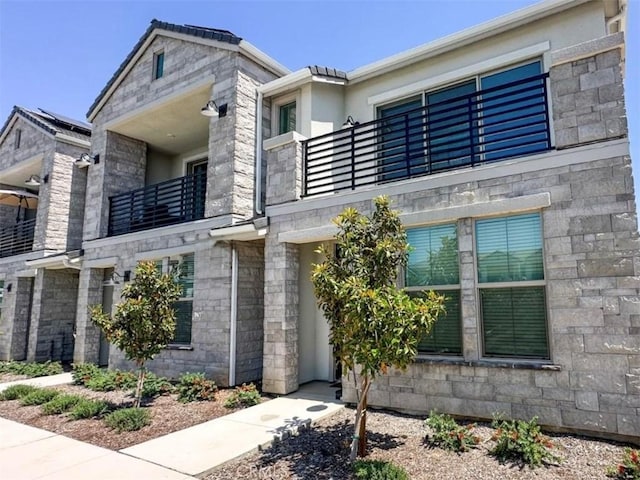 480 W Balsam Ln, Clovis, CA 93611 - view of front facade with a balcony, stucco siding, and stone siding