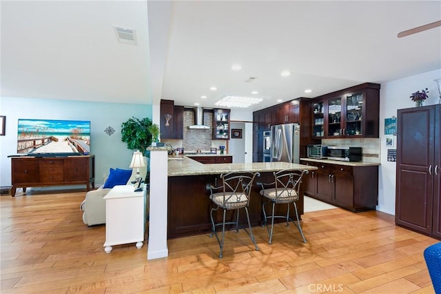 25355 Auld Ave, Hemet, CA 92544 - kitchen with appliances with stainless steel finishes, light wood-style flooring, tasteful backsplash, wall chimney range hood, and recessed lighting