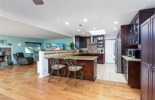 25355 Auld Ave, Hemet, CA 92544 - kitchen with wall chimney range hood, a kitchen bar, freestanding refrigerator, glass insert cabinets, and recessed lighting