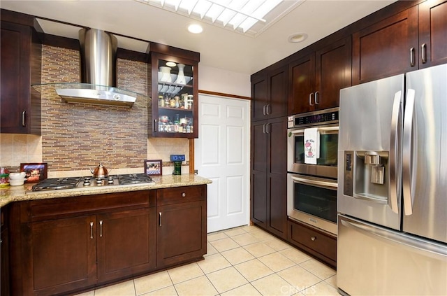 25355 Auld Ave, Hemet, CA 92544 - kitchen with stainless steel appliances, light tile patterned floors, wall chimney range hood, decorative backsplash, and glass insert cabinets