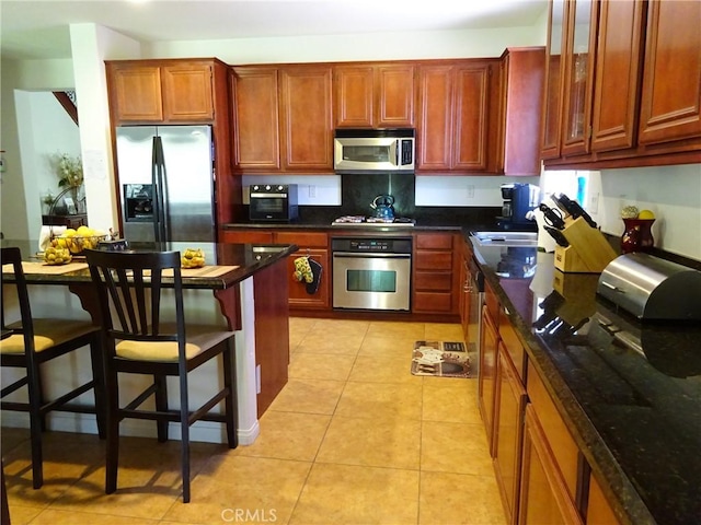 43890 Moccasin Pl, Lancaster, CA 93536 - kitchen featuring stainless steel appliances, a breakfast bar area, glass insert cabinets, and light tile patterned floors
