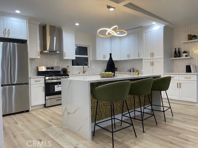 20406 Londelius St, Winnetka, CA 91306 - kitchen with appliances with stainless steel finishes, wall chimney range hood, backsplash, a center island, and white cabinets