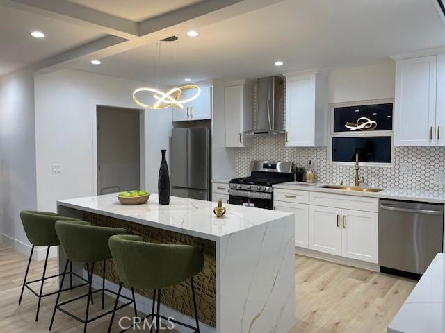 20406 Londelius St, Winnetka, CA 91306 - kitchen featuring appliances with stainless steel finishes, wall chimney exhaust hood, light wood-type flooring, a chandelier, and recessed lighting