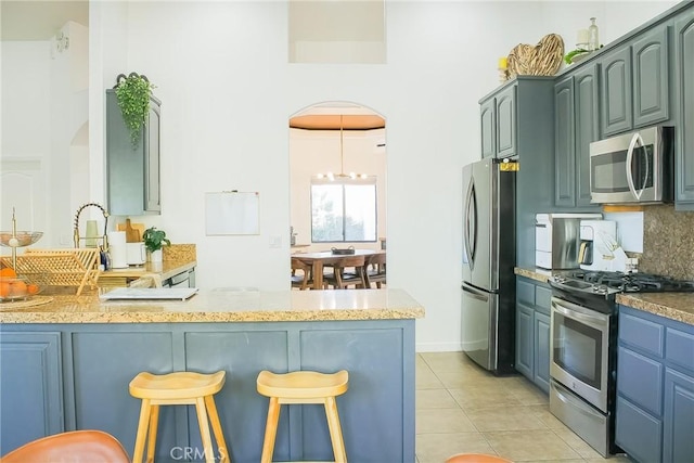 7525 Whitney Ave, Yucca Valley, CA 92284 - kitchen with appliances with stainless steel finishes, arched walkways, a peninsula, a kitchen breakfast bar, and a towering ceiling