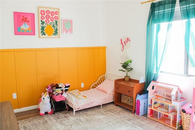 7525 Whitney Ave, Yucca Valley, CA 92284 - bedroom featuring multiple windows, a decorative wall, wood finished floors, and wainscoting