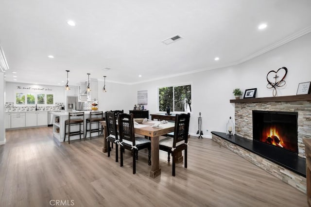 9604 Tunney Ave, Northridge, CA 91324 - dining room featuring plenty of natural light, recessed lighting, a stone fireplace, light wood-style flooring, and crown molding