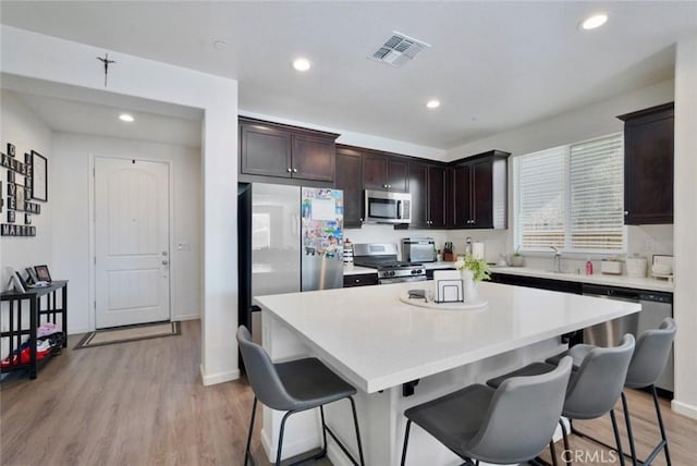 453 Daffodil Dr, Merced, CA 95341 - kitchen featuring appliances with stainless steel finishes, a center island, a breakfast bar area, light countertops, and dark brown cabinets