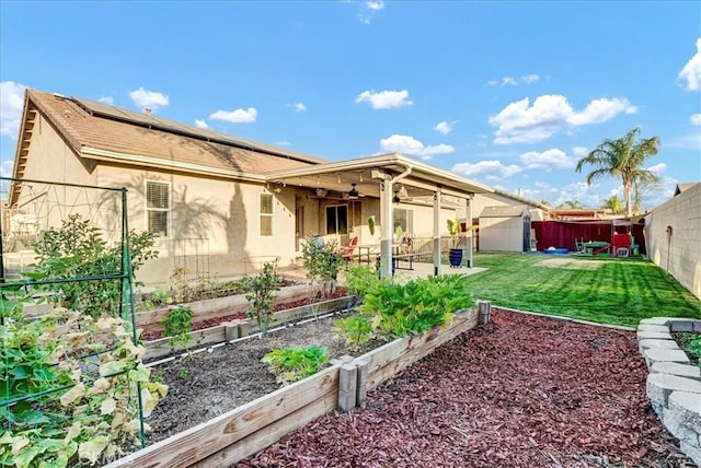 695 Crescent Ln, Lemoore, CA 93245 - rear view of house featuring a garden, a ceiling fan, a fenced backyard, a storage shed, and roof mounted solar panels