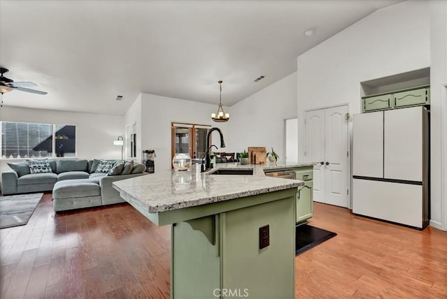 695 Crescent Ln, Lemoore, CA 93245 - kitchen featuring green cabinetry, freestanding refrigerator, lofted ceiling, light wood-style flooring, and a center island with sink