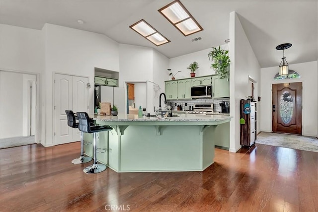 695 Crescent Ln, Lemoore, CA 93245 - kitchen with green cabinets, freestanding refrigerator, stove, high vaulted ceiling, and a kitchen bar