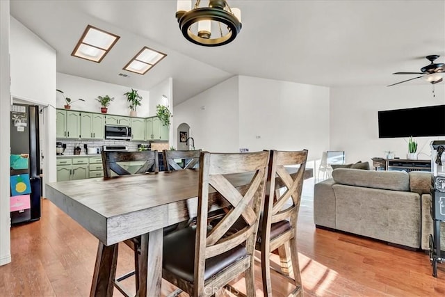 695 Crescent Ln, Lemoore, CA 93245 - dining space with light wood-type flooring, ceiling fan, vaulted ceiling, a chandelier, and arched walkways