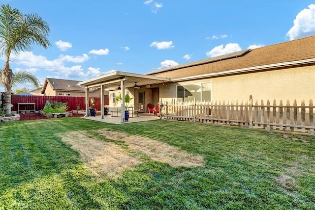 695 Crescent Ln, Lemoore, CA 93245 - back of house featuring ceiling fan, a patio area, a fenced backyard, solar panels, and stucco siding