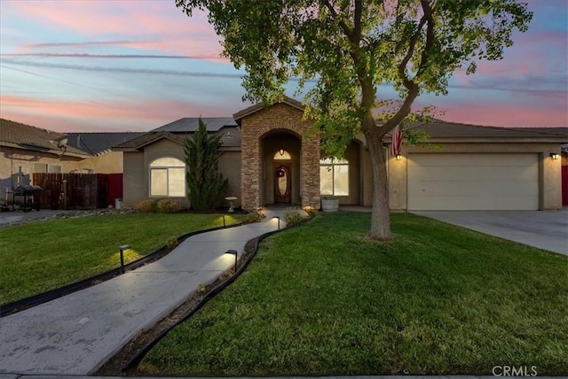695 Crescent Ln, Lemoore, CA 93245 - view of front of home featuring roof mounted solar panels, a garage, stucco siding, concrete driveway, and stone siding
