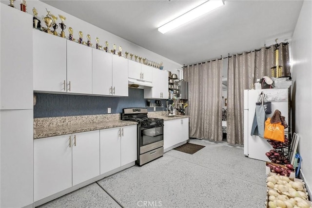 16614 Trailblazer Ave, Chino, CA 91708 - kitchen featuring stainless steel range with gas cooktop, under cabinet range hood, white cabinetry, refrigerator, and dark aggregate flooring