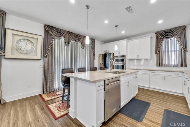 16614 Trailblazer Ave, Chino, CA 91708 - kitchen featuring appliances with stainless steel finishes, wood finished floors, an island with sink, light countertops, and white cabinets