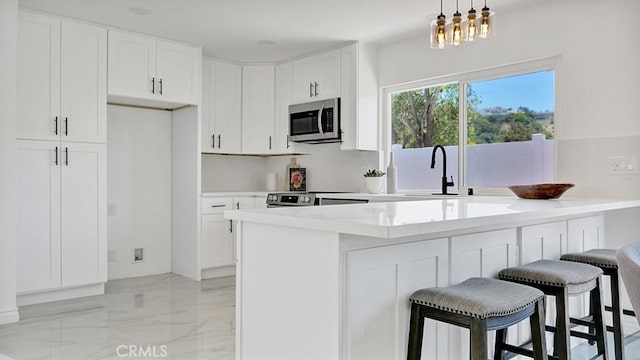 23231 Cheswald Dr, Laguna Niguel, CA 92677 - kitchen featuring stainless steel microwave, white cabinetry, a breakfast bar, a peninsula, and light marble finish floors
