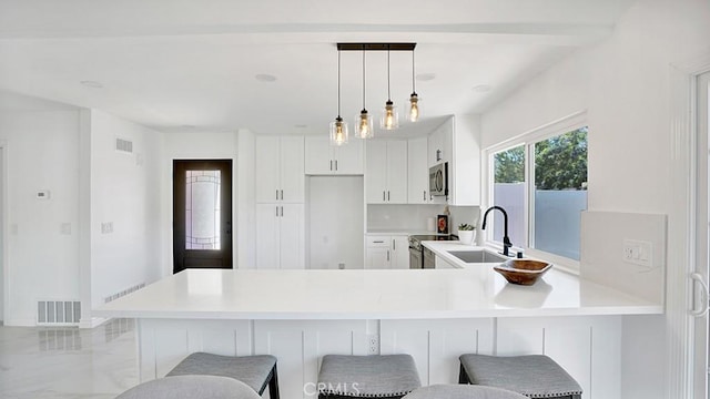 23231 Cheswald Dr, Laguna Niguel, CA 92677 - kitchen featuring appliances with stainless steel finishes, light countertops, a peninsula, a kitchen breakfast bar, and white cabinetry
