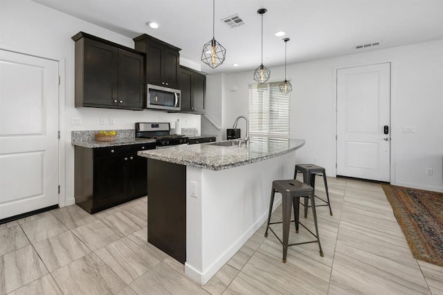4192 Camino Campana, Oceanside, CA 92057 - kitchen with appliances with stainless steel finishes, light stone counters, a kitchen bar, an island with sink, and pendant lighting