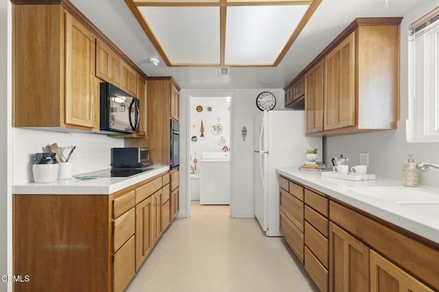 4907 Island View St, Oxnard, CA 93035 - kitchen with washer / dryer, black appliances, light countertops, tasteful backsplash, and brown cabinets
