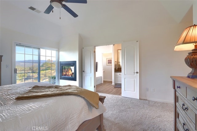 31008 Longview Ln E, Coarsegold, CA 93614 - bedroom featuring access to outside, a multi sided fireplace, vaulted ceiling, a ceiling fan, and light colored carpet
