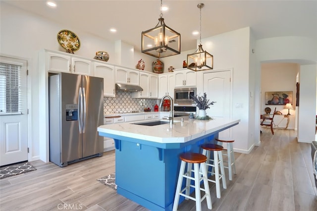 31008 Longview Ln E, Coarsegold, CA 93614 - kitchen with appliances with stainless steel finishes, under cabinet range hood, white cabinets, decorative backsplash, and a breakfast bar area