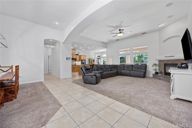 403 Stone Cross Dr, Bakersfield, CA 93312 - living room with light carpet, ceiling fan, light tile patterned floors, a fireplace, and arched walkways