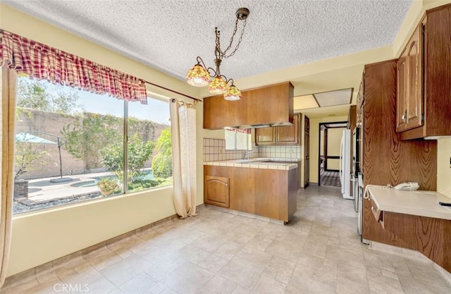 1023 Don Pablo Dr, Arcadia, CA 91006 - kitchen featuring brown cabinetry, a peninsula, backsplash, a textured ceiling, and tile counters