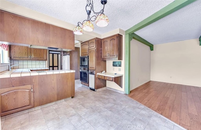 1023 Don Pablo Dr, Arcadia, CA 91006 - kitchen featuring tile countertops, stainless steel microwave, oven, a textured ceiling, and brown cabinets