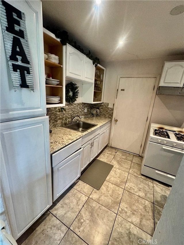 1203 W 134th Pl, Compton, CA 90222 - kitchen with white gas range, open shelves, white cabinetry, backsplash, and under cabinet range hood