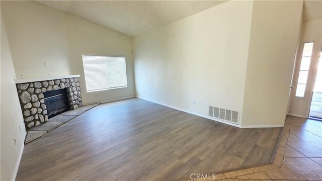 37432 Whitehall Ln, Palmdale, CA 93550 - unfurnished living room featuring vaulted ceiling, wood finished floors, and a stone fireplace