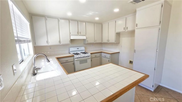 37432 Whitehall Ln, Palmdale, CA 93550 - kitchen with white range with gas stovetop, under cabinet range hood, tile countertops, a peninsula, and recessed lighting