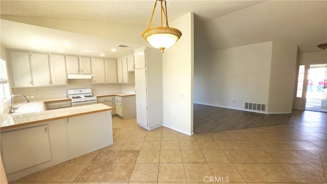 37432 Whitehall Ln, Palmdale, CA 93550 - kitchen with gas range gas stove, under cabinet range hood, a peninsula, light tile patterned floors, and tile countertops