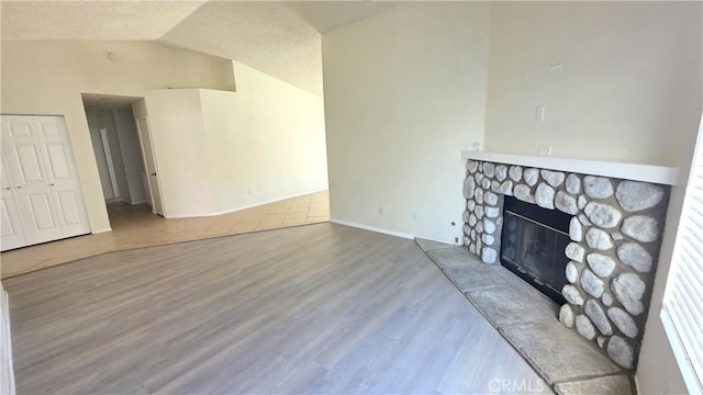 37432 Whitehall Ln, Palmdale, CA 93550 - unfurnished living room featuring lofted ceiling, wood finished floors, a stone fireplace, and a textured ceiling