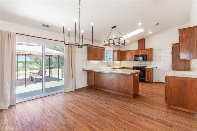 5335 Play Doe Ln, Paso Robles, CA 93446 - kitchen featuring black appliances, vaulted ceiling, a peninsula, tasteful backsplash, and brown cabinets