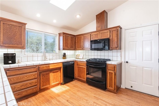 5335 Play Doe Ln, Paso Robles, CA 93446 - kitchen featuring black appliances, tile counters, vaulted ceiling, light wood-style floors, and decorative backsplash