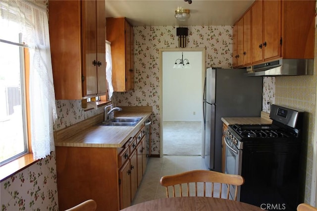 836 N 10th Ave, Upland, CA 91786 - kitchen with stainless steel gas range, under cabinet range hood, wallpapered walls, brown cabinetry, and light countertops