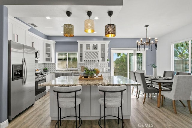 5612 Sprague Ave, Cypress, CA 90630 - kitchen with stainless steel appliances, tasteful backsplash, white cabinets, a chandelier, and light wood-style flooring