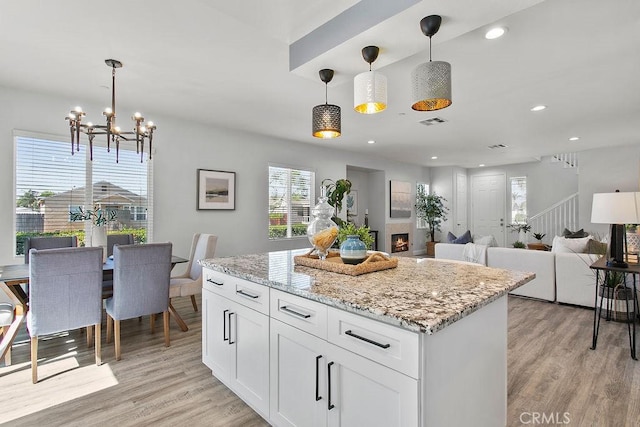 5612 Sprague Ave, Cypress, CA 90630 - kitchen featuring light wood finished floors, a chandelier, white cabinets, light stone countertops, and pendant lighting