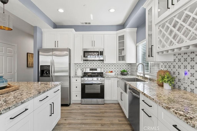 5612 Sprague Ave, Cypress, CA 90630 - kitchen featuring appliances with stainless steel finishes, white cabinetry, light stone counters, wood finished floors, and glass insert cabinets
