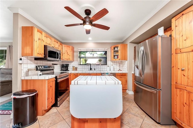 29639 Delphinium Ave, Canyon Country, CA 91387 - kitchen featuring appliances with stainless steel finishes, tile countertops, a ceiling fan, ornamental molding, and backsplash