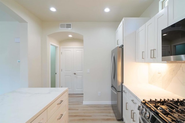 1295 Haglar Unit 1, Chula Vista, CA 91913 - kitchen with stainless steel appliances, light wood finished floors, light stone countertops, white cabinetry, and arched walkways