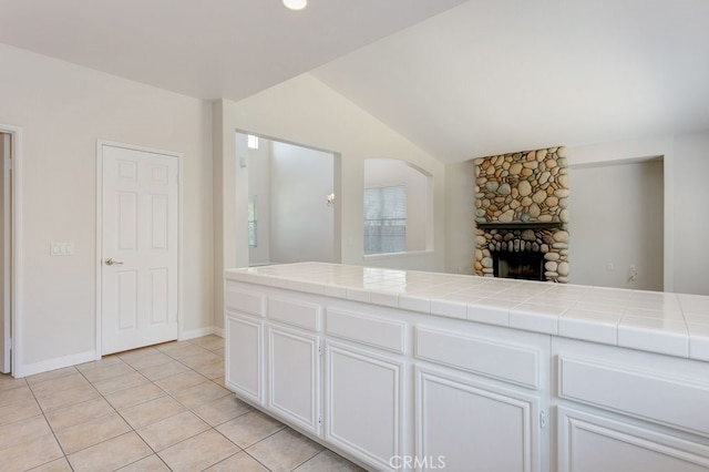3450 Lake Park Ave, Fallbrook, CA 92028 - kitchen with tile counters, light tile patterned floors, white cabinetry, vaulted ceiling, and a fireplace