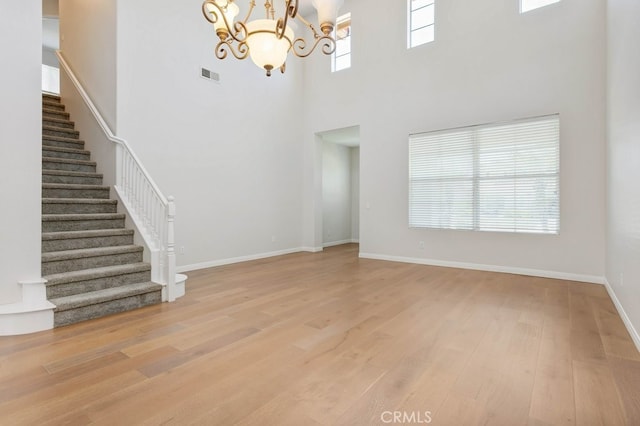 3450 Lake Park Ave, Fallbrook, CA 92028 - unfurnished living room with stairway, light wood-style flooring, a chandelier, and a towering ceiling
